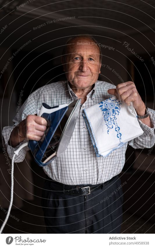 Elderly man ironing textile in room elderly aged senior chore housework routine mature focus home demonstrating male show concentrate casual fabric domestic