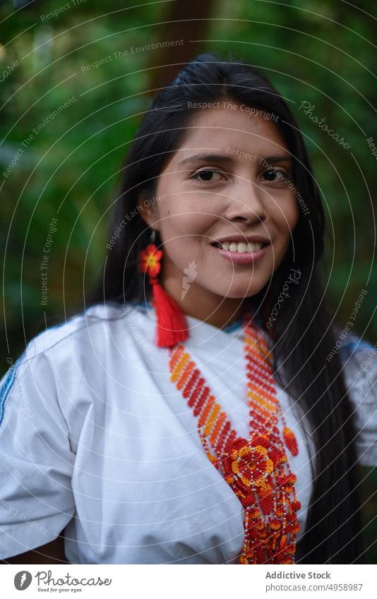 Young native Arhuaco woman in forest young indigenous portrait Colombia happy smile close up 20s nature exterior outside necklace handmade earrings crafts