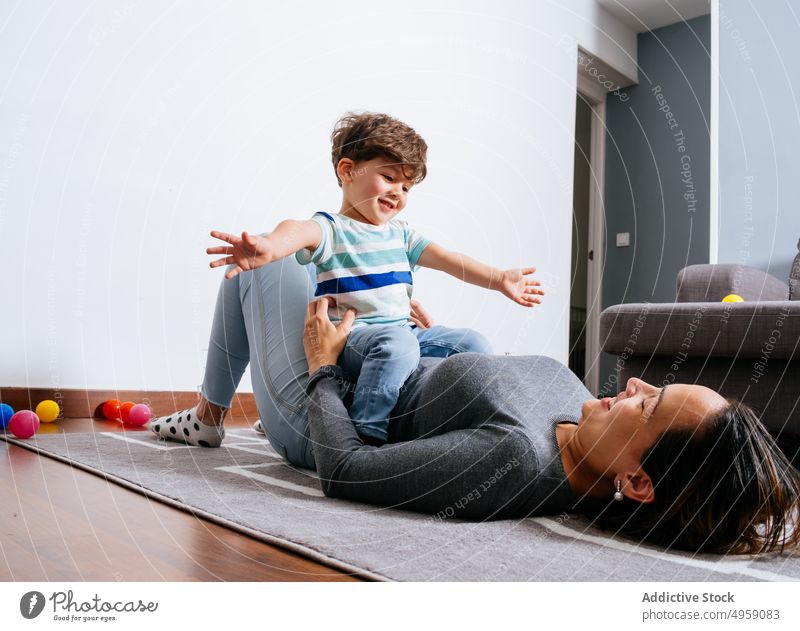 Mother playing with son on floor mother happy cozy home bonding fun woman boy kid child toddler love lying smile little childhood care laugh together parent