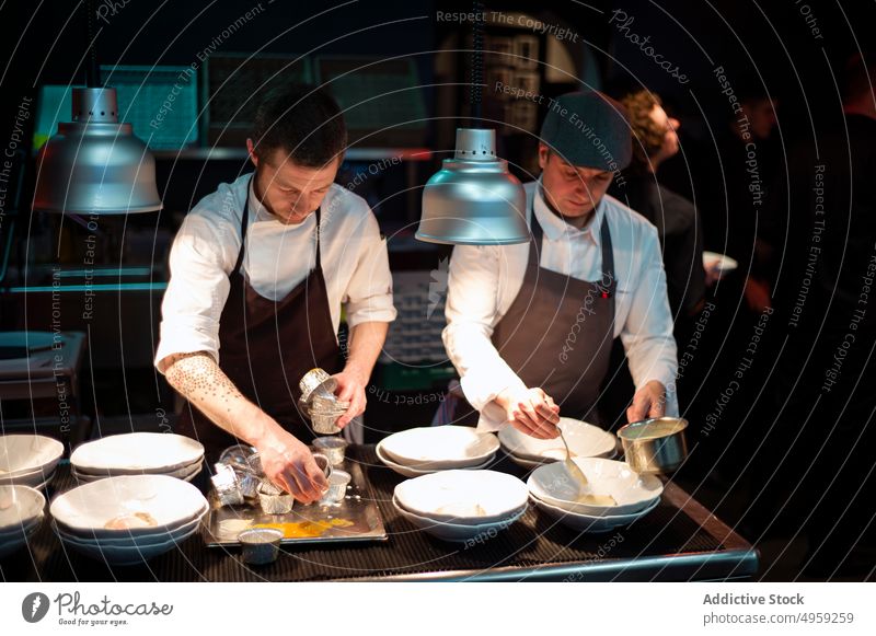 Cooks serving meal on restaurant kitchen cooks food dish chef man professional plate uniform male people cuisine table dinner preparation cooking work person