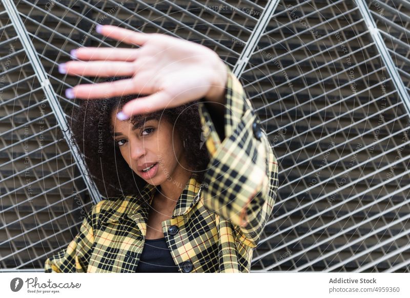Stylish ethnic woman showing stop gesture against grid fence control style defense private prohibit reject negate portrait prevent hide restriction forbidden