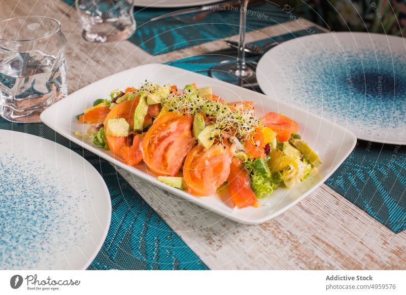 Plate with tasty tomato salad in restaurant healthy food meal lunch dinner menu vitamin mix plate glass red wine alcohol sprout avocado slice fresh vegetable