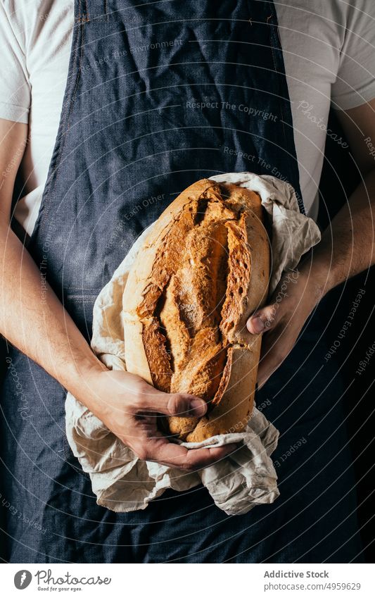 Anonymous man showing crunchy bread in bakery demonstrate loaf delicious baked nutrition kitchen crispy fresh tasty artisan cuisine male casual apron culinary