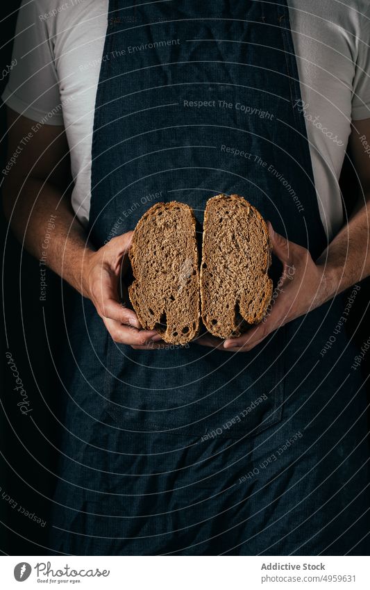 Anonymous man showing slices whole wheat bread in bakery demonstrate loaf delicious baked nutrition kitchen crispy fresh tasty artisan cuisine casual apron