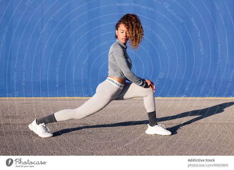 Determined sportswoman stretching on pavement in town athlete training workout determine shadow practice healthy lifestyle perform concentrate motivation