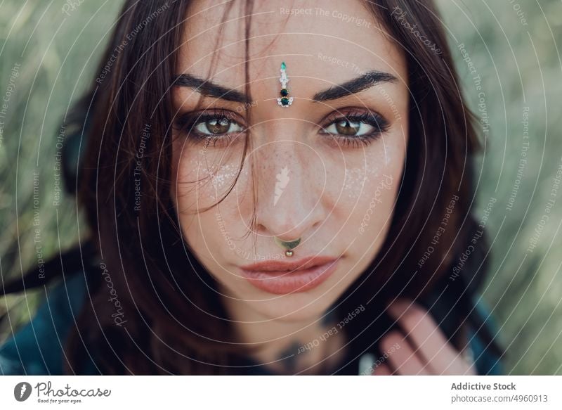 Woman looking at camera with gaze in park woman eye bindi appearance eyelashes brunette jewelry piercing tranquil fashion female forehead tradition allure