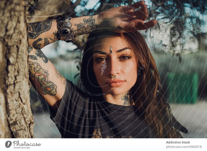 Charismatic stylish adult woman with tattoos and piercing on street trendy cool confident appearance brunette relax personality carefree female bracelet plant