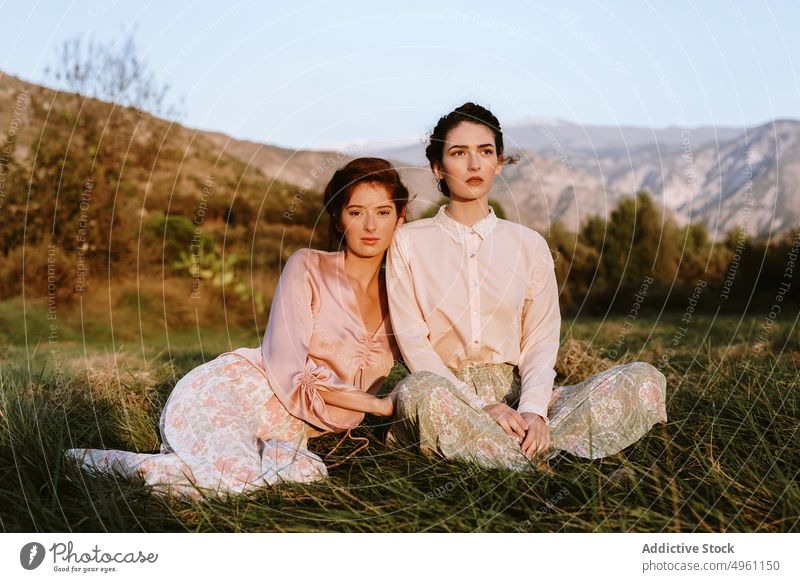 Cute young women with classic outfit lying down on grass alone apparel beautiful beauty best friends blooming caucasian clothing cool couple cute dress elegant