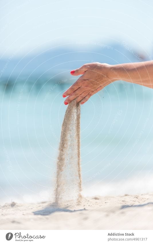 Unrecognizable woman with handful of sand on seashore beach through finger summer vacation pour sunny female seaside sunlight summertime holiday coast ocean