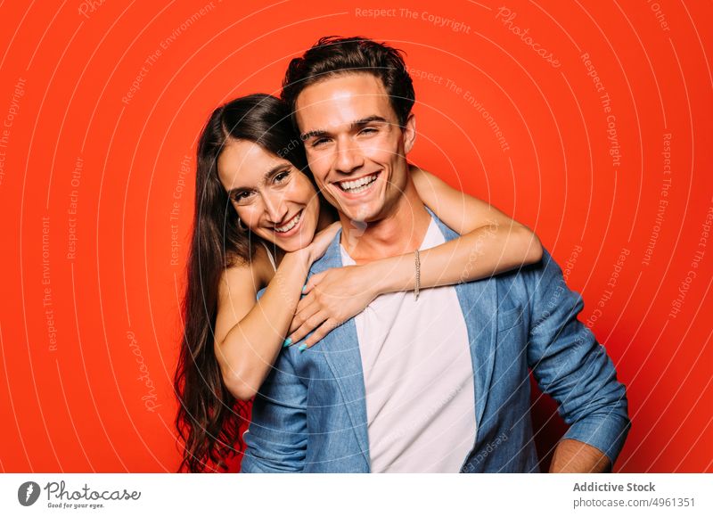 Content couple in trendy clothes on red background embrace relationship fashion love romantic style happy colorful portrait girlfriend beloved bright stylish