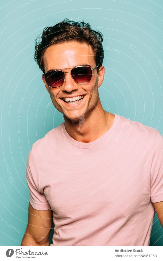 Content masculine model in sunglasses on blue background fashion style content macho friendly man portrait accessory contemporary happy toothy smile