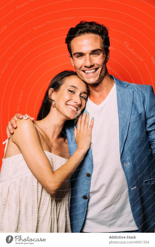 Content couple in trendy clothes on red background embrace relationship fashion love romantic style happy colorful portrait girlfriend beloved bright stylish