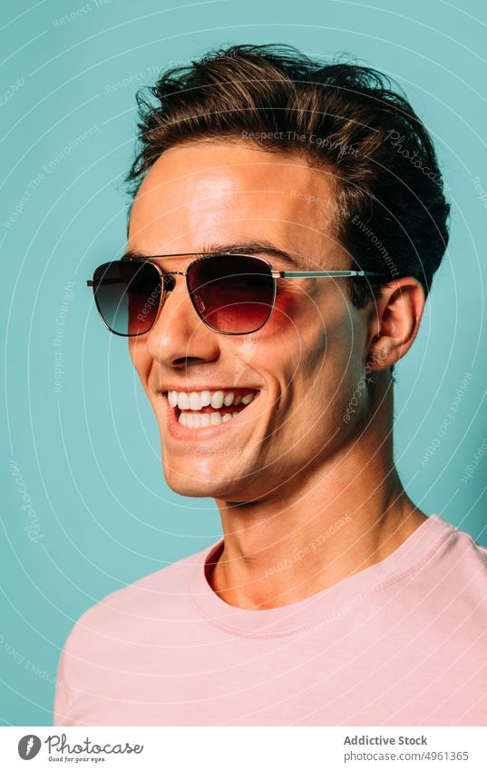 Content masculine model in sunglasses on blue background close-up fashion style content macho friendly man portrait accessory contemporary happy toothy smile