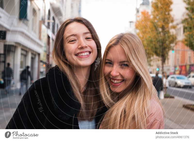 Smiling female friends looking at camera in city women best friend charming smile positive street stroll weekend madrid spain young happy cheerful joy trendy