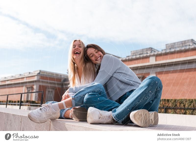 Positive women embracing in city and looking at camera hug friend best friend friendship smile cuddle weekend spend time female madrid spain together street