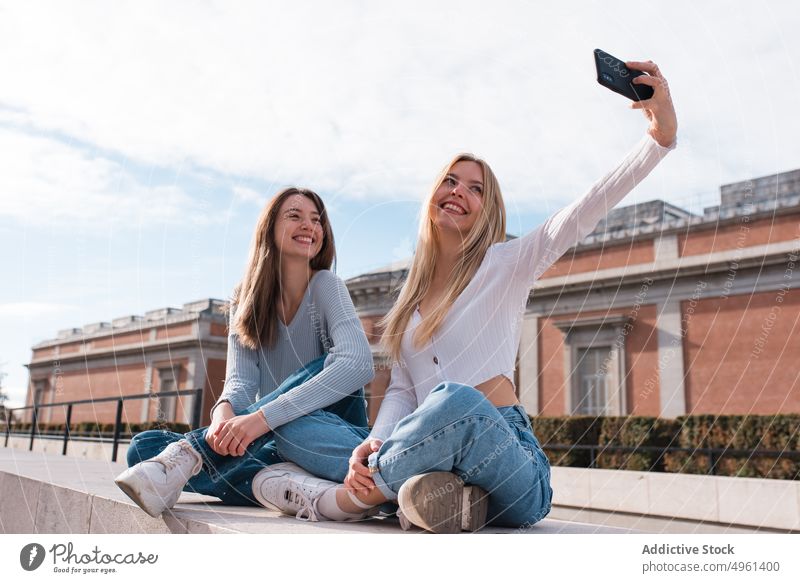 Positive women taking selfie on smartphone in city best friend cheerful having fun memory moment self portrait female madrid spain mobile together using smile