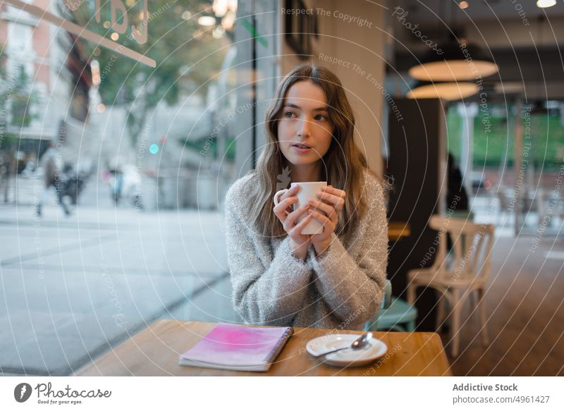 Calm woman chilling in cafe at weekend coffee cup tranquil dreamy thoughtful relax female table beverage drink rest hot drink young enjoy notebook lady street