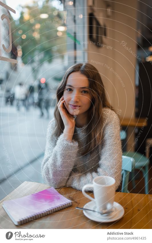 Calm woman chilling in cafe at weekend coffee cup tranquil dreamy thoughtful relax female table beverage drink rest hot drink young enjoy notebook lady street