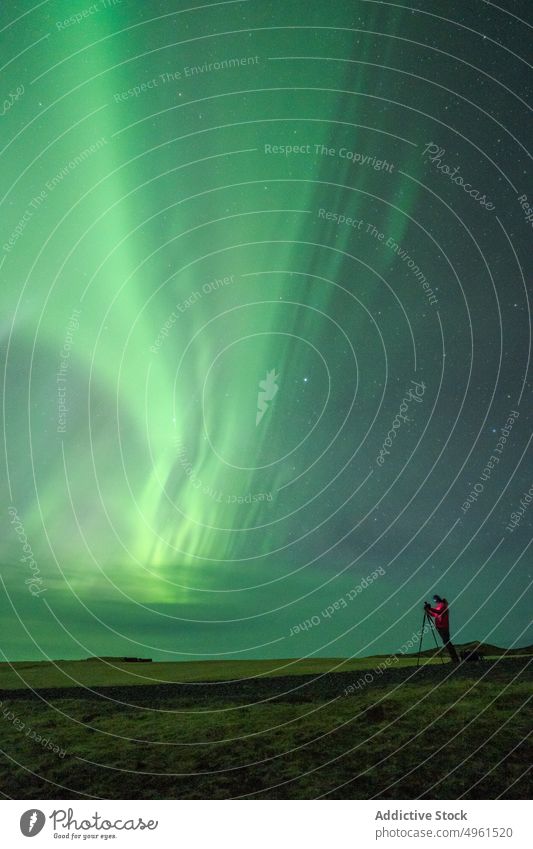 Traveler taking photo of northern lights at night photographer aurora borealis take photo traveler sky green polar lofoten islands norway shiny photo camera