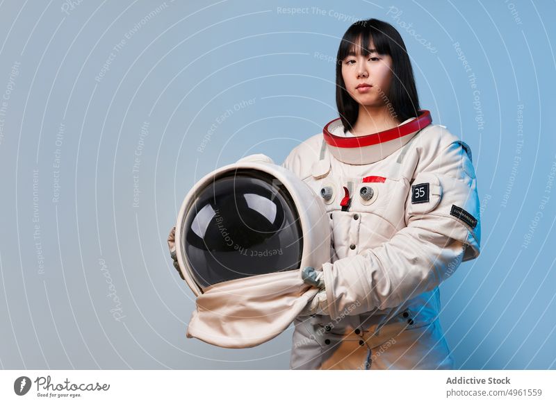 Serious Asian astronaut with helmet woman spacesuit serious mission ready uniform safety portrait female asian ethnic chinese japanese young protect costume