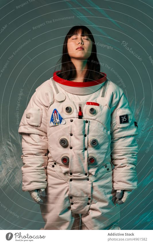 Calm Asian cosmonaut with closed eyes in studio woman ready mission calm serious spacesuit futuristic modern female neon young asian chinese japanese ethnic