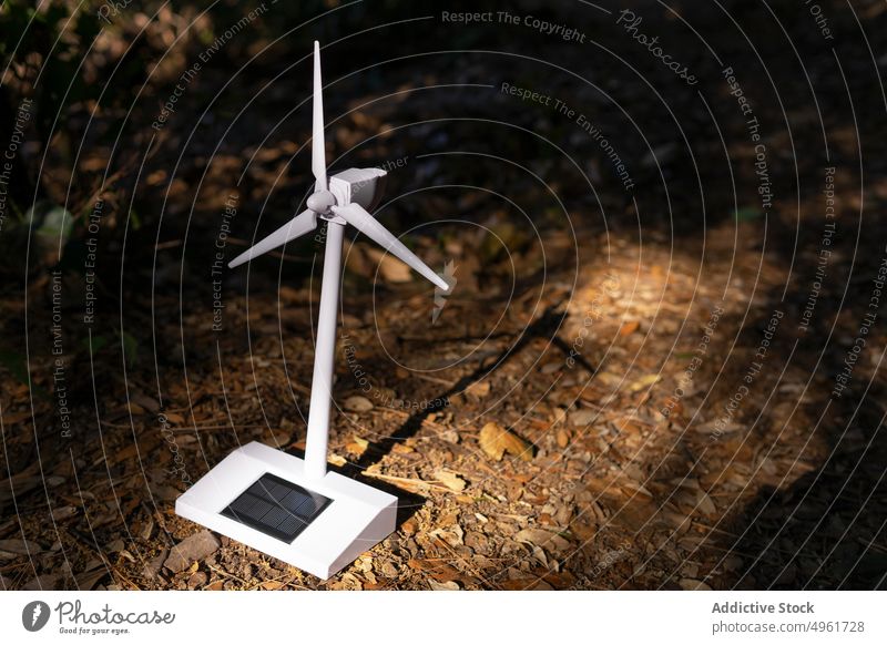 Modern wind turbine miniature placed on ground in forest windmill energy nature toy solar renewal power resource tree propeller sunlight generator eco