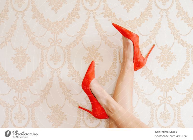 Woman in shoes crossing legs on wall woman legs crossed stiletto ornament wallpaper style elegant footwear bright red high heels feminine vivid vibrant daytime