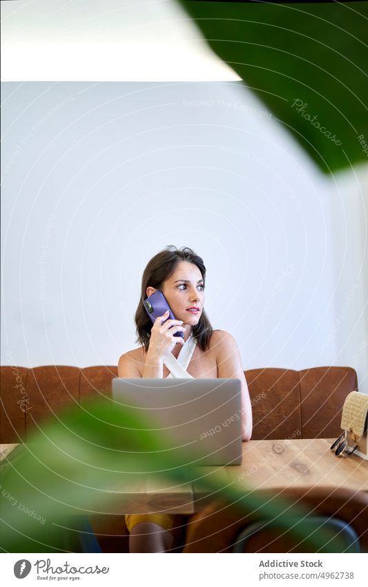 Businesswoman talking on smartphone and browsing laptop during work businesswoman project cafe multitask entrepreneur remote busy freelance mobile focus female