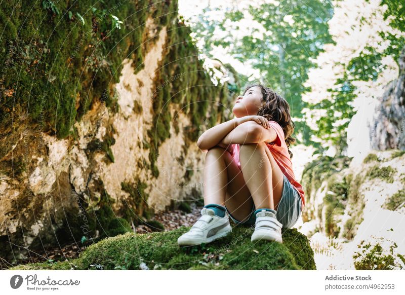 Girl sitting on stone in nature girl countryside summer weekend moss daytime admire season sunny kid arms crossed rock child rough trip casual boulder weather