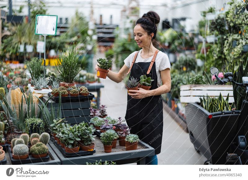 Shot of a young woman working with plants in a garden centre plant nursery smiling positivity nature gardening cultivate growth hobby freshness growing flora