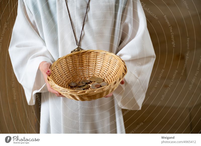 Person in white robe holds beige rattan basket with change in hands collectors Donation gift Church Church tax Money small change Church service Help Basket