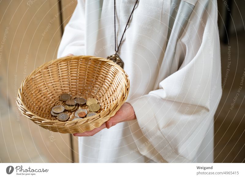Person in white robe holds beige rattan basket with change in hands Rattan basket altar boy Church collectors Church tax Donation gift Church life small change