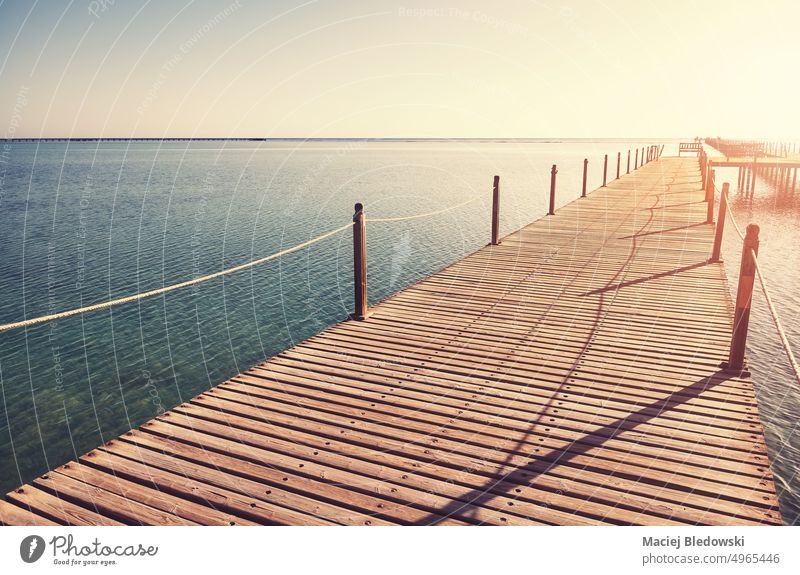 Wooden pier at sunrise, color toning applied. travel sea ocean water nature tranquil sky vacation wood horizon sunset jetty blue destination scenic shore island
