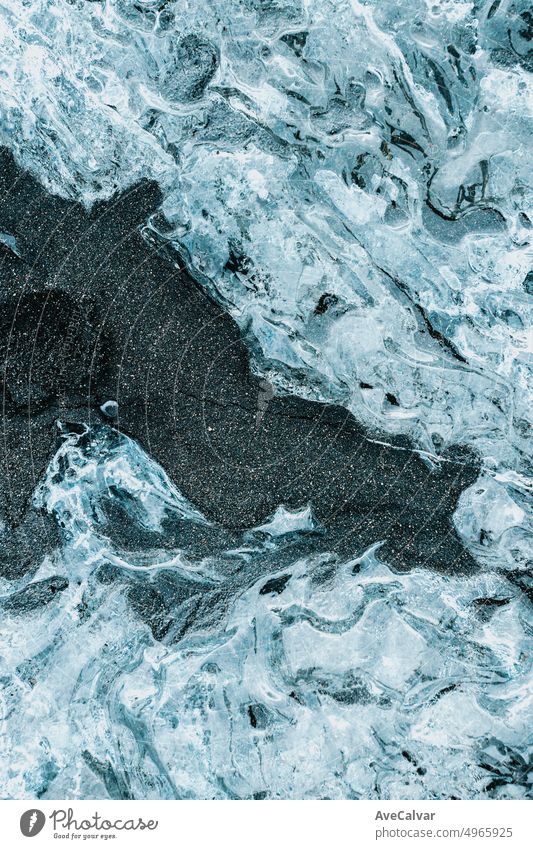 Natural scratched ice frozen surface design as texture or background witch black sand.Wallpaper with copy space. Ice blocks from at Jökulsárlón glacier lagoon, Vatnajökull National Park