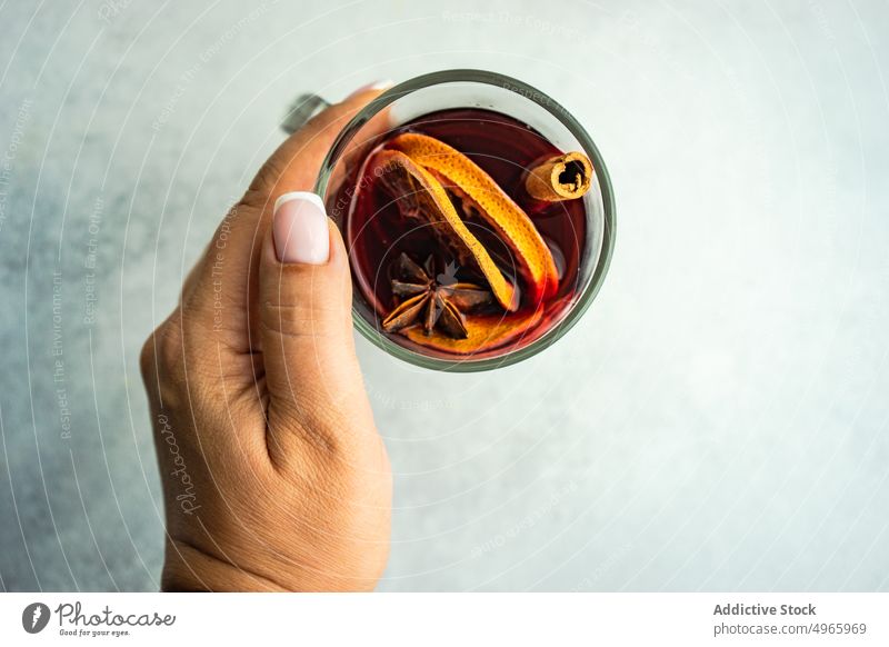 Anonymous woman drinking mulled wine with spices anise star berry beverage christmas cinnamon festive hand hold holiday orange red slice sticks winter spicy