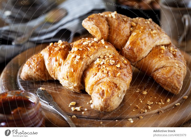 Croissants with crushed hazelnuts on cutting board croissant brioche french puff pastry bakery vegan cereal jam marmalade morning breakfast baked homemade dough