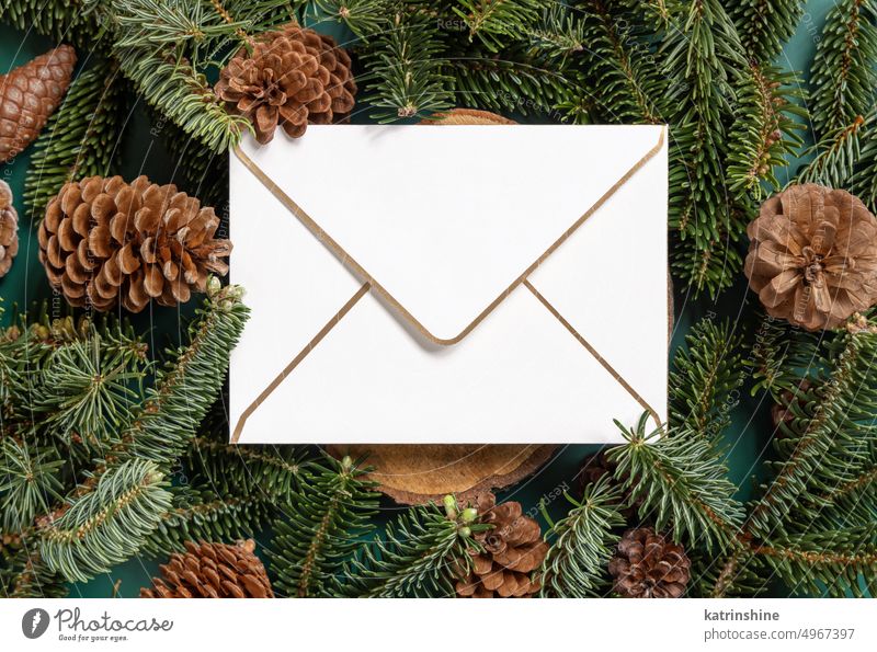 Christmas  blank envelope between fir branches and pine cones on green top view christmas mockup holiday New year template winter paper greeting white