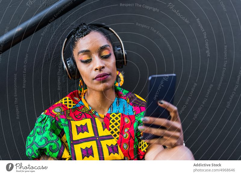 Ethnic woman using smartphone on steps street listen music social media meloman style female young ethnic street style urban colorful gadget device connection