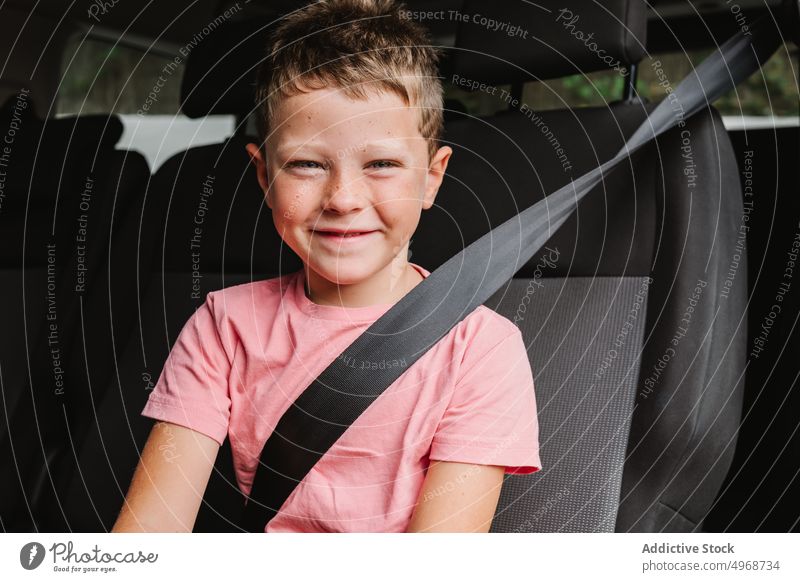 Cheerful boy sitting in car smile backseat road trip happy weekend travel passenger casual kid journey positive transport auto vehicle ride child cheerful