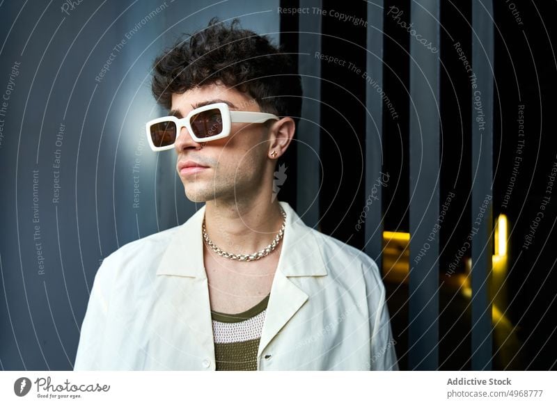 Stylish young guy wearing sunglasses man style fashion trendy curly hair street style portrait confident outfit male serious appearance personality self assured
