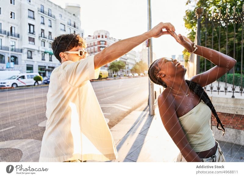 Happy diverse couple dancing on street dance happy together spin around road urban laugh style having fun girlfriend boyfriend young multiracial multiethnic