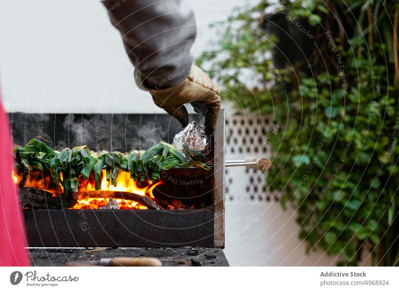 Unrecognizable person grilling calcots on terrace cook onion bbq traditional authentic cuisine culinary food catalonian foil charcoal hot burn barbecue spain