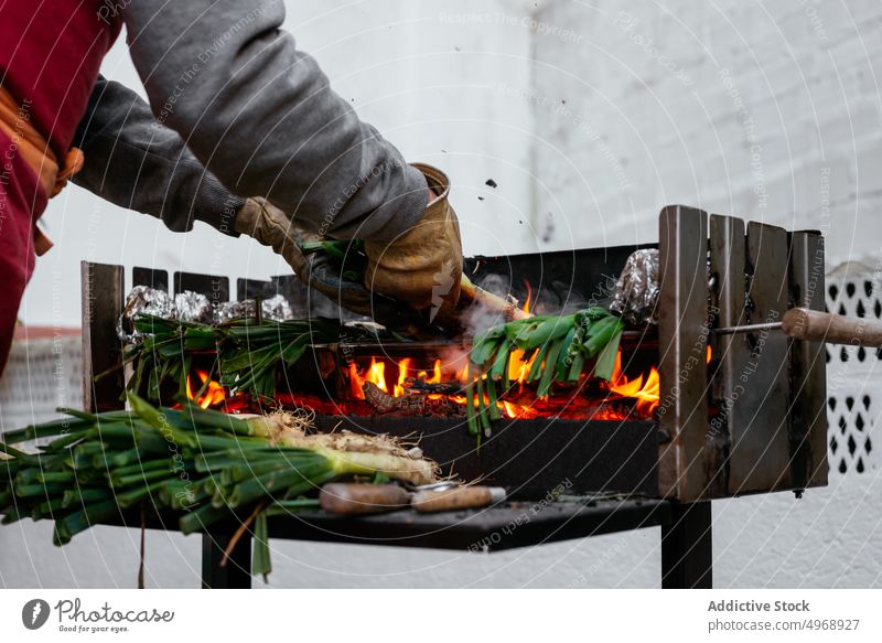 Unrecognizable person grilling calcots on terrace cook onion bbq traditional authentic cuisine culinary food catalonian foil charcoal hot burn barbecue spain