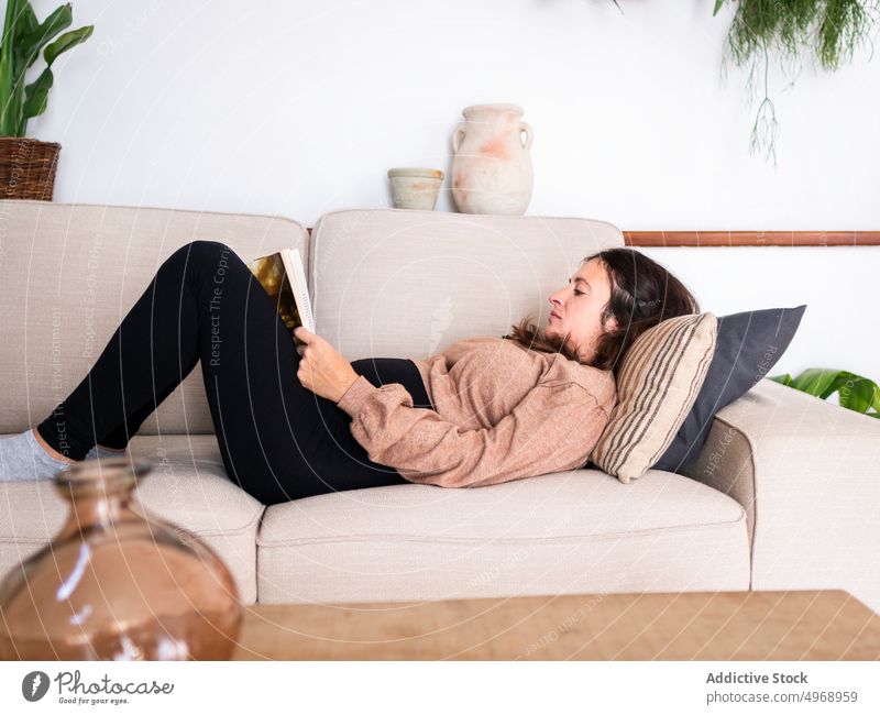 Woman lying on sofa with book woman couch hobby living room modern apartment concentrate serious female read leisure focus home literature knowledge pastime