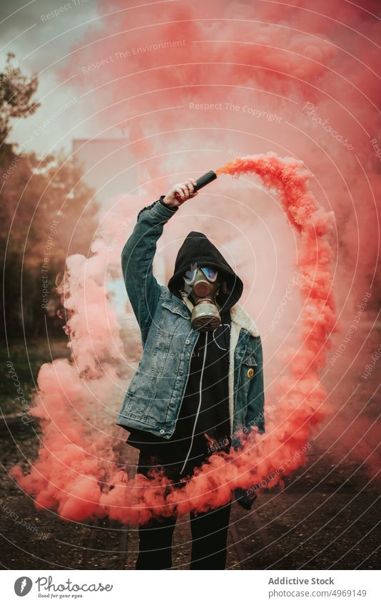 Person holding smoke bomb on street person gas cloud smog steam pink colorful signal rebellion respirator gas mask grenade fume fog toxic chemical flow