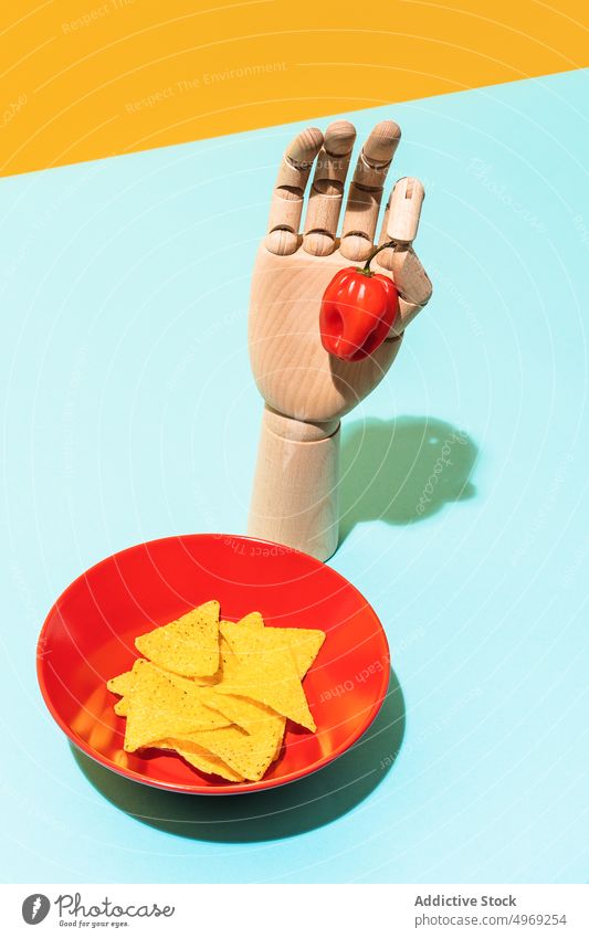 Artificial arm with habanero pepper placed near tortilla chips hand tradition dish hot concept bo
