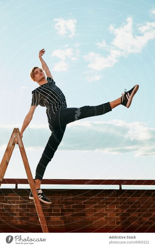 Young choreographer posing on stepladder on roof athlete equilibrium stretching flexible talented graceful empty young man male dancer performer handsome