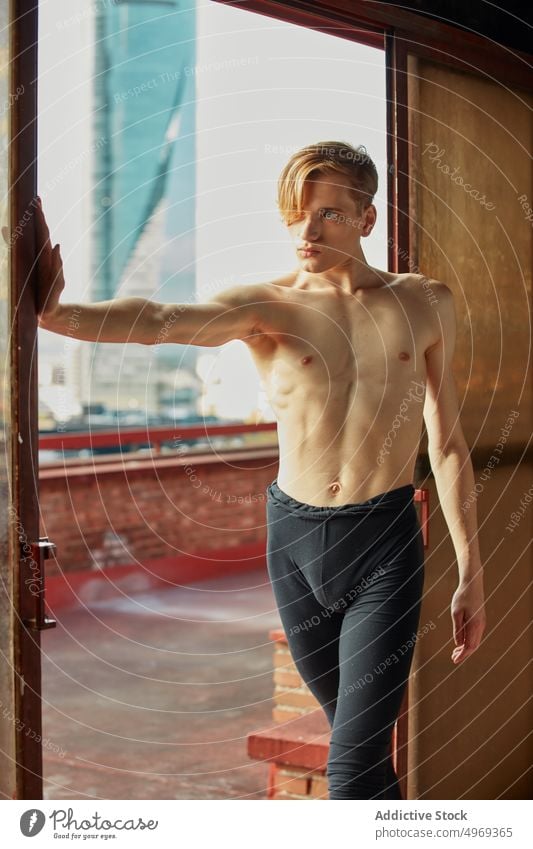 Young ballet dancer posing in twine in room performing splits talented graceful flexible empty stretching young man male athlete performer handsome attractive