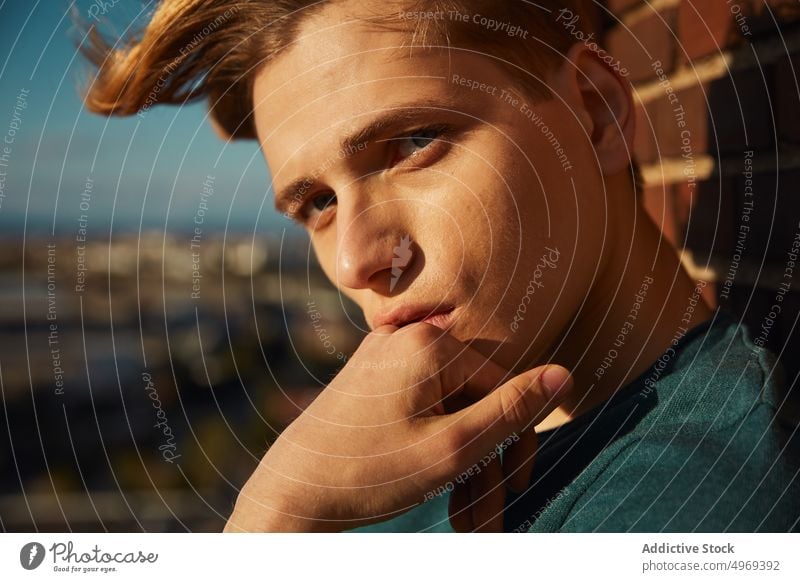 Young blond man resting on roof building relaxed enjoyment urban trendy comfortable stylish young male handsome cute attractive happy serious mature fashionable
