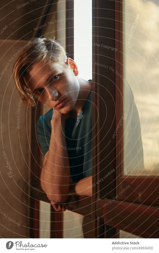 Young man looking out window from street handsome relaxed urban trendy stylish model summer young male blond attractive happy serious mature fashionable elegant